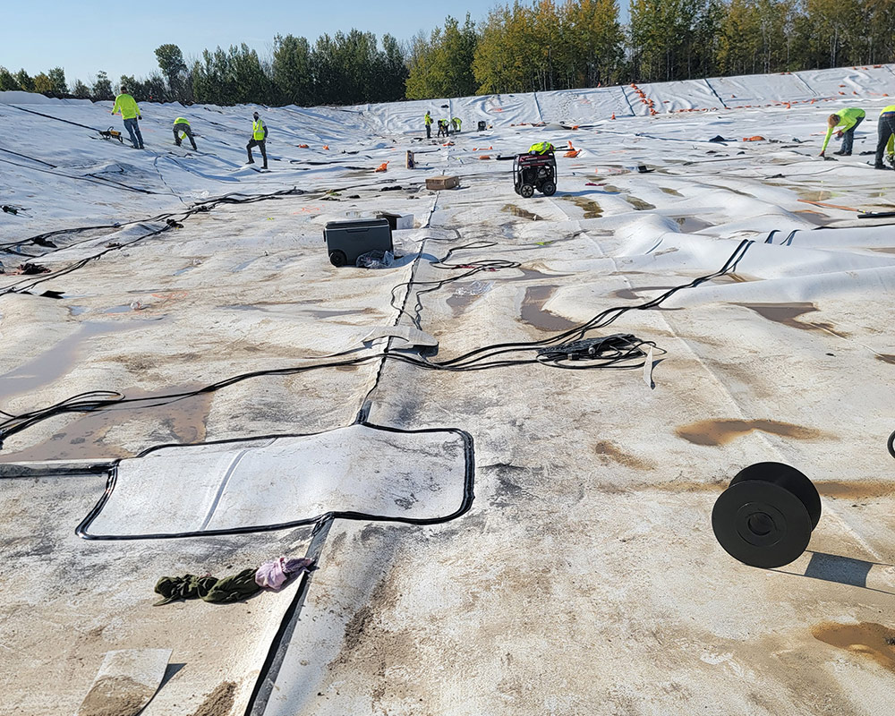 Ongoing Installation of White/Black Textured Liner for a Storage Pond. Fusion Welding and Testing in Progress.